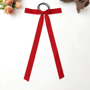 Detail view of a premium red velvet bow hair tie with long ribbons on white background