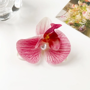 Detail of pink orchid hair clip with realistic flower texture and center pearl accent