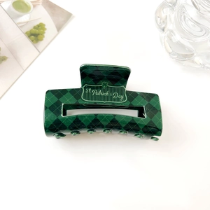 Détail de la pince à cheveux à carreaux vert et noir pour la Saint-Patrick avec logo