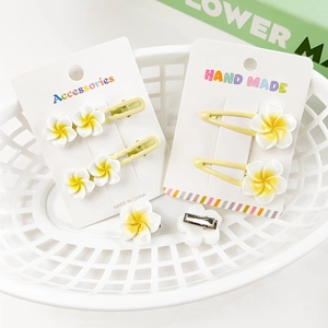 Detailed close-up of yellow and white frangipani flower hair clips in a white basket