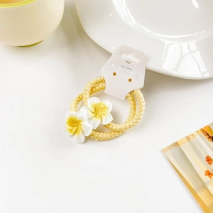 Detail of yellow flower hair ties set on a white card display with warm lifestyle decor