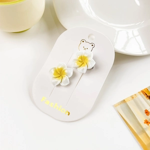 Close-up of white and yellow gradient frangipani flower stud earrings on fashion card