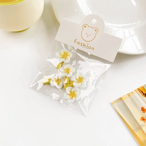 Detail of five white and yellow plumeria hair clips in clear package with card