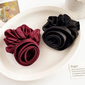 Detail view of red and black satin rose scrunchies on a white decorative tray