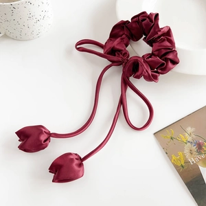 Detailed shot of dark red satin scrunchie with long ribbons and tulip-shaped tips