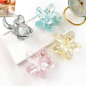 Close-up of four matte frangipani flower hair claws with iridescent laser finish