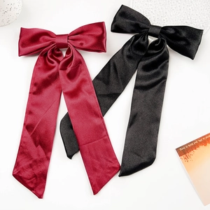 Nahaufnahme von eleganten weinroten und schwarzen Satin-Haarschleifen mit langen Bändern