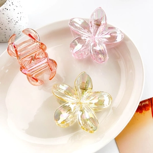 Detailed view of iridescent resin flower hair clips in coral and pastel yellow colors