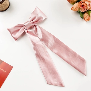 Detail einer zartrosa Satin-Schleifen-Haarklammer mit langen Bändern auf weiß