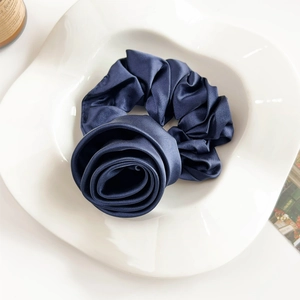 Detailed close-up of navy blue satin rose hair scrunchie with silk gloss finish