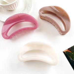 Detail of crescent moon hair claws in rose pink, caramel brown, and creamy white finishes