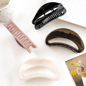 Detailed view of glossy crescent hair claws in black, pink, amber, and cream colors