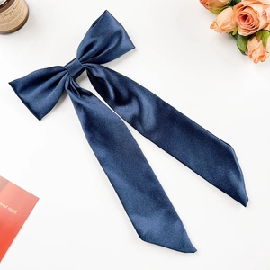 Detail einer eleganten dunkelblauen Satin-Haarschleife mit langen Bändern auf Weiß