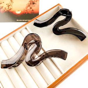 Close-up of elegant S-shaped hair claws in glossy black and smoke grey resin material