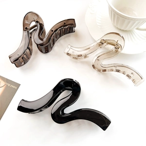 Detailed view of S-shaped hair claws in translucent grey, champagne, and solid black