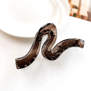 Detailed view of large crescent wave hair claw clip in transparent brown acrylic material