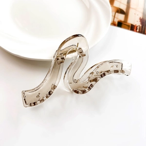 Detail of large wave S-shaped hair claw clip in translucent amber with gold metal spring