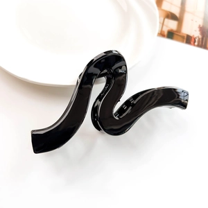 Close-up of a glossy black wave-shaped hair claw clip with a polished minimalist design