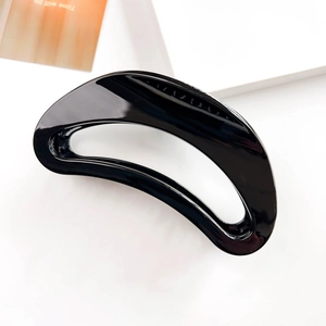 Macro shot of black crescent moon hair claw clip with glossy mirror finish on white background