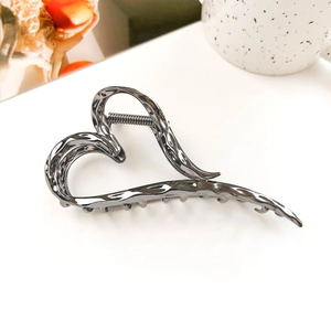 Detail of liquid metal hollow heart hair claw with dark chrome finish and secure teeth