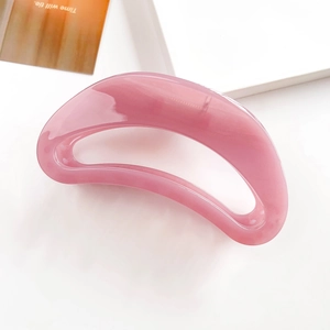Detail of pink translucent crescent hair claw clip made of glossy resin on white background