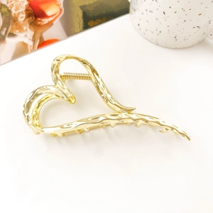 Close-up of golden liquid metal heart hair claw clip with elegant wavy texture
