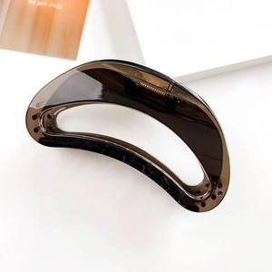 Detail of dark brown translucent hair claw clip with sleek cutout and gold metal spring