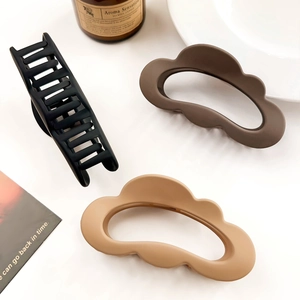 Three matte cloud hair clips in brown and black on a white background with props