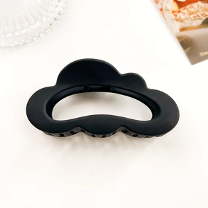 Close-up of matte black cloud hair claw clip with hollow design on minimalist background