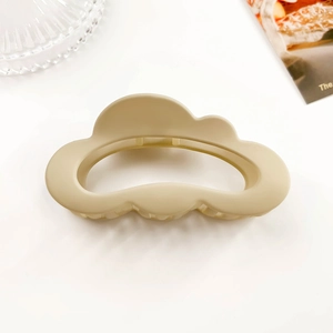 Detail view of a cream-colored cloud hair claw with a matte finish and hollow design