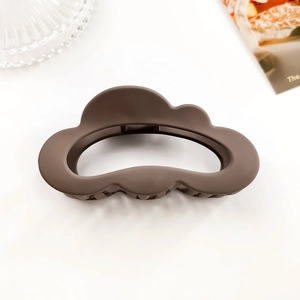 Detail view of coffee brown cloud-shaped matte hair claw clip with serrated teeth on white background