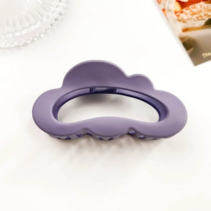 Detail shot of a matte purple cloud-shaped hair claw clip on a minimalist white surface