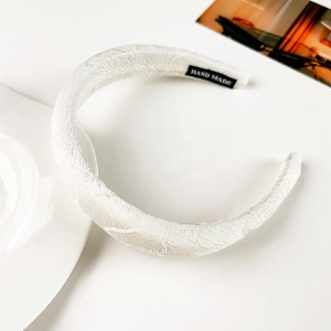 Vue détaillée du serre-tête large à fleurs blanches avec tissu jacquard texturé de qualité
