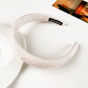 Détail du serre-tête en dentelle beige fait main avec rembourrage et étiquette