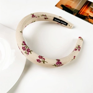 Détail du serre-tête floral beige rembourré avec étiquette fait main et texture coton