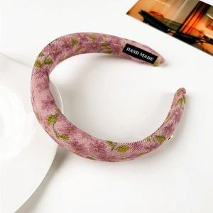 Détail du serre-tête en velours côtelé lavande à motifs floraux et étiquette faite main