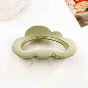 Detail view of light green matte cloud-shaped hair claw clip on a minimalist white background