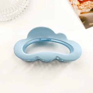 Detail shot of a matte light blue cloud-shaped hair claw clip with a hollow design