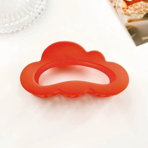 Macro view of matte orange cloud hair claw clip with non-slip teeth on white background