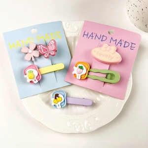 Détail de barrettes à cheveux colorées papillon et fruits sur carte artisanale