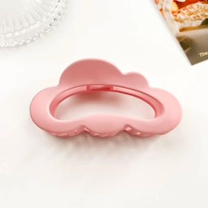 Detail of a matte pink cloud-shaped hair claw clip with a hollow wave silhouette