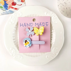 Détail de deux jolies barrettes papillon et fleur sur carte rose sur assiette en porcelaine