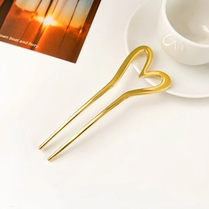 Close-up of golden U-shaped hair pin featuring a polished metal heart on a white background
