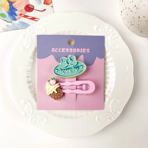 Détail de la pince à cheveux rose avec cornet de glace et nœud bleu sur une assiette