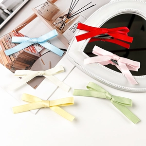 Detailed set of six colorful satin ribbon bow hair clips on a decorative desk setup