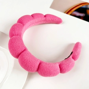 Close-up of a pink padded sponge headband with soft terry cloth texture for skincare