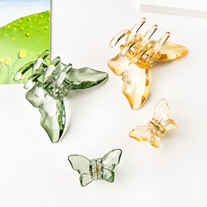 Detail of transparent butterfly hair claws in amber and green with gold metal springs