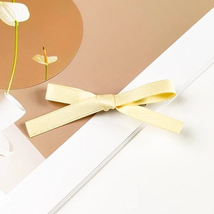 Detail shot of a bright yellow ribbon bow hair clip with clear woven texture and metal grip