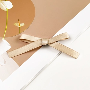 Detailed view of champagne gold satin ribbon hair clip with high-quality silky texture