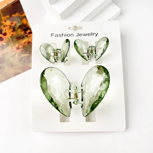 Close-up of three translucent green butterfly hair clips set on a white display card